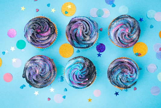 Top view of six vanilla cupcakes on blue party background