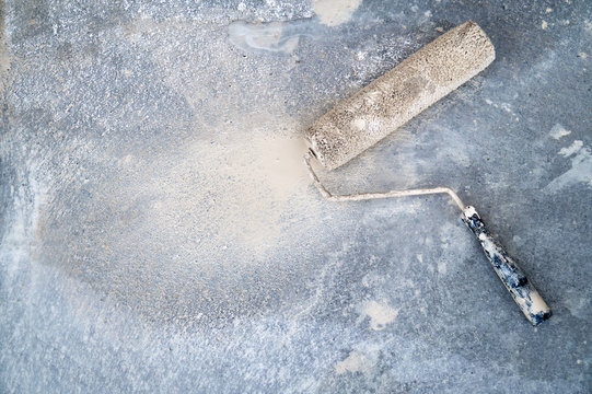 Dirty paint roller on the dirty concrete floor