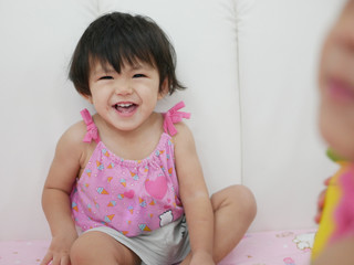 Selective focus of pretty little Asian baby girl, 18 months old, smiling and laughing at home -...