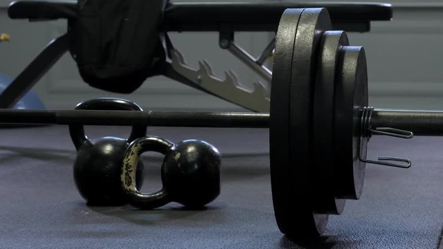Moody darker 4k footage of free weights and metal plates in home garage gym