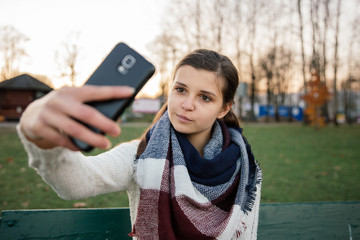 Dziewczyna robi sobie selfie telefonem w parku. Jesień.