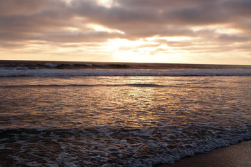 A southern California, USA sunset in summer with the fading sunlight shining over the shore of the Pacific ocean