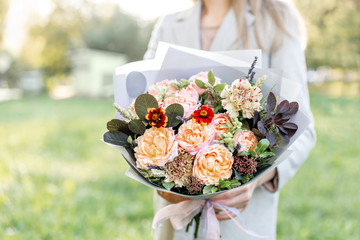 Close-up beautiful autumn bouquet in hands. flower arrangement with various flowers. green lawn on...