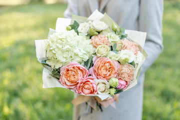 Close-up beautiful spring bouquet in hands. delicate flower arrangement with pink and green pastel...
