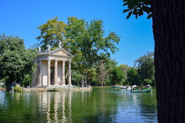 Fototapeta na wymiar Rome Italy. Garden of Villa Borghese. Lake with boats and temple of Aesculapius,(tempio di Esculapio)
