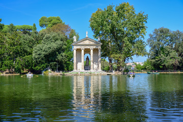 Fototapeta na wymiar Rome Italy. Garden of Villa Borghese. Lake with boats and temple of Aesculapius, (tempio di Esculapio)