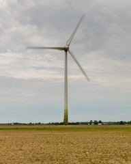 Wind Turbine In An Empty Field Under A Cloudy Grey Sky
