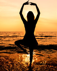 Teen Girl In A Dress With Long Hair At The Beach In Silhouette During Sunset In A Ballet Pose