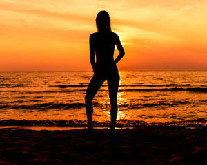 Teen Girl In A Bathing Suit With Long Hair At The Beach In Silhouette During Sunset In A Casual Pose