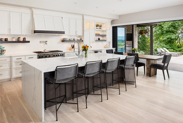Kitchen interior in new luxury home with hardwood floors, waterfall island, dining room table, and...