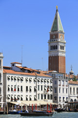 Fototapeta premium Venice canal, boat traffic, mooring posts and St Mark's Campanile, bell tower, in the background - famous place, Veneto, Italy; attraction, sightseeing, vacations, travel, romance, tourism.