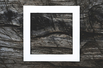 f overhead top view of white square frame on top of dark wooden scratched surface mock up concept, creative layout