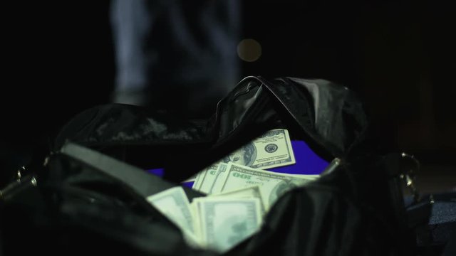 Male bandit opening car trunk and throwing moneybag, bank robbery crime