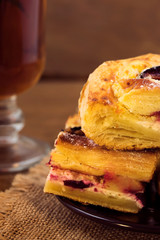 Pieces of homemade puff pastry with baked plums and cottage cheese, tea with mint in a glass, close-up, vertical frame.