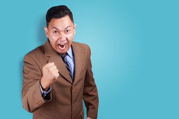 Angry Asian businessman showing his fist, ready to fight while screaming