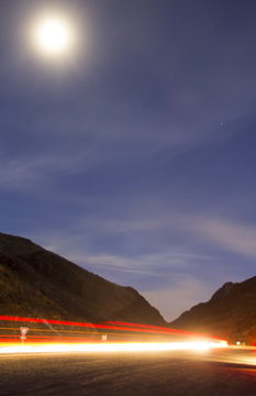 Long Exposure Traffic Light Trails through a mountain canyon at night with dark blue sky