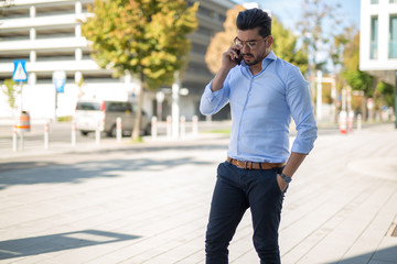 Successful young businessmantalking on his smartphone outside