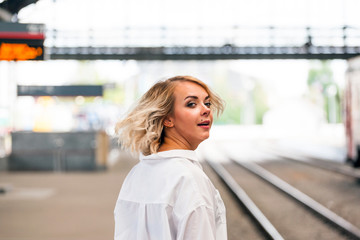 young beautiful girl turns her head back at the old railway station