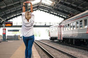 young beautiful girl in a white shirt and blue jeans goes on the platform at the old railway station