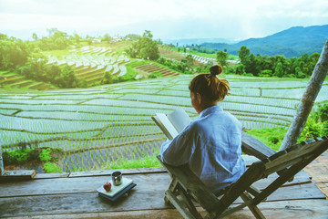 Asian woman travel nature. Travel relax. sit reading book the balcony of the resort. View of the field on the Moutain in summer. Thailand