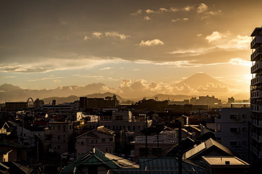 Bright sunset illuminating a small city with mount Fuji looming in the background
