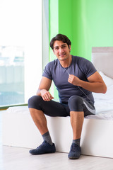 Young handsome man doing morning exercises in the hotel room