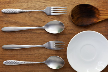 Spoon fork and white dish on the wooden background,top view use for background in kitchen and food.
