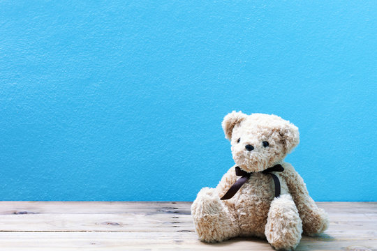 Teddy bear on old wood in front blue wall background.