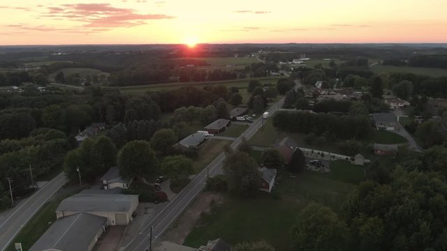 A slow forward high angle aerial establishing wide shot view of a western Pennsylvania sunset over a small countryside residential neighborhood. Pittsburgh suburbs.  	
