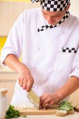 Young professional cook preparing salad at kitchen
