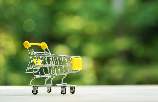 Little shopping cart on a shiny green forest background