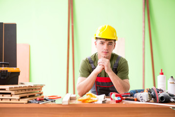 Young man carpenter working in workshop 