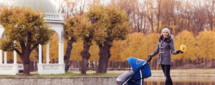 Mother playing in park with her toddler baby. Mom and son over seasonal autumn background.