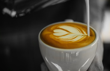 Barista pouring milk in coffee cup .