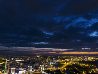 Night aerial view of downtown. Urban architectures with illumination under dramatic sky