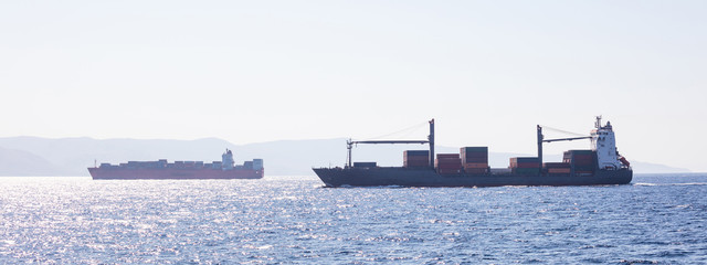Two container ships for international transport sail full of cargo. Sea commerce, sky background,...