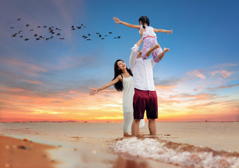 Happy asian family - father, mother, kid takes up in the air together with fun along sunset sea beach. Travel, active lifestyle, parents with children on summer vacations..