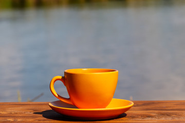 Cup of coffee on the wooden table near the river