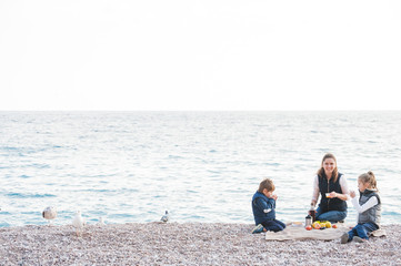 happy family consisting of three person on sea shore picnic in cold weather