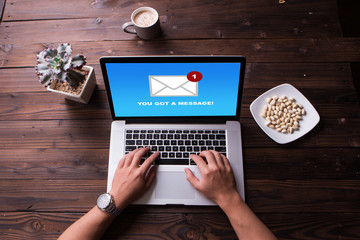 Top view of man hands working on laptop and got a mail message with wooden desk background