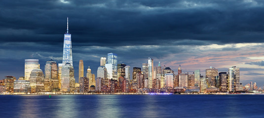 Obraz premium New York City Manhattan downtown skyline at night with skyscrapers lit over Hudson River