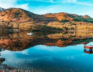Early morning reflections with loan boat  at Loch Earn, Scotland