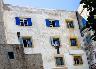 Fototapeta na wymiar Amazing Morocco, incredible EssaoAmazing Morocco, incredible EssaoAmazing Morocco, incredible Essaouira, medina, the wall of the house, windows with yellow platbands and blue shutters