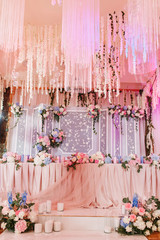 Richly decorated with flowers and fabrics reception for a wedding Banquet. Pastel pink colors