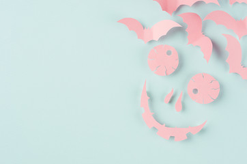 Funny pink halloween monster of cut paper cartoon with swarm bats as hair on pastel mint blue background.