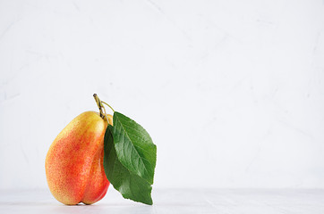 Ripe pear williams with green leaves on soft white wood board. Sweet summer fruits.
