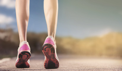 Runner feet running on running road closeup on shoe. woman fitness sunrise jog concept...