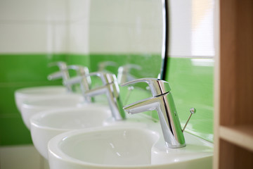 several water taps stand in a row in the bathroom