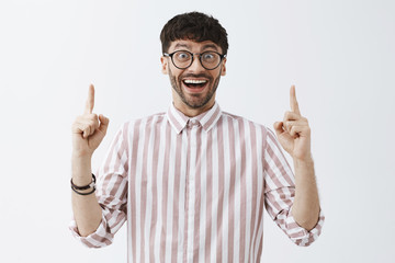 Excited good-looking happy man with beard and dark cool hairstyle in black glasses and striped...
