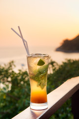 Mojito cocktail drink with evening sunset on beach background